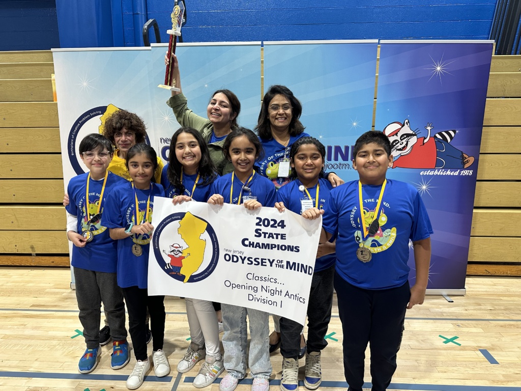 Several children in blue team shirts with a teacher holding their 350 Award banner and tropy. 